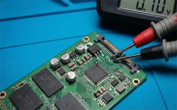 Mesure de tension au multimètre sur la carte électronique (PCB) d'un SSD pour diagnostiquer une surtension ou un court-circuit sur les régulateurs d'alimentation.